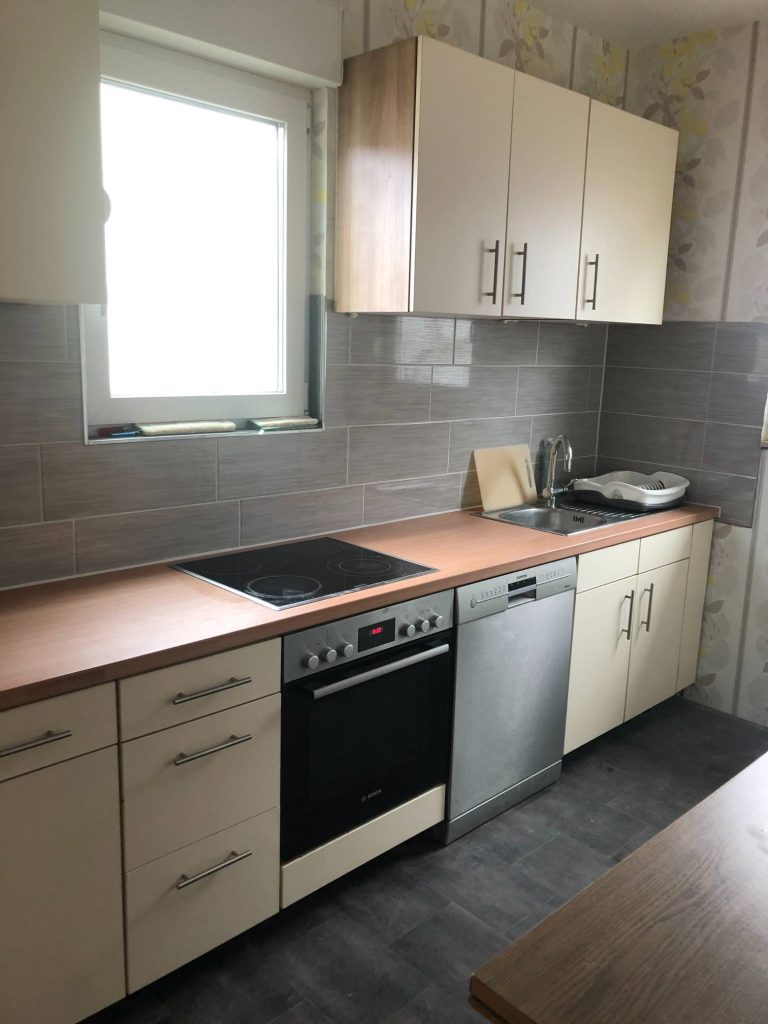 Eine Einbauküche mit grauen Fliesen