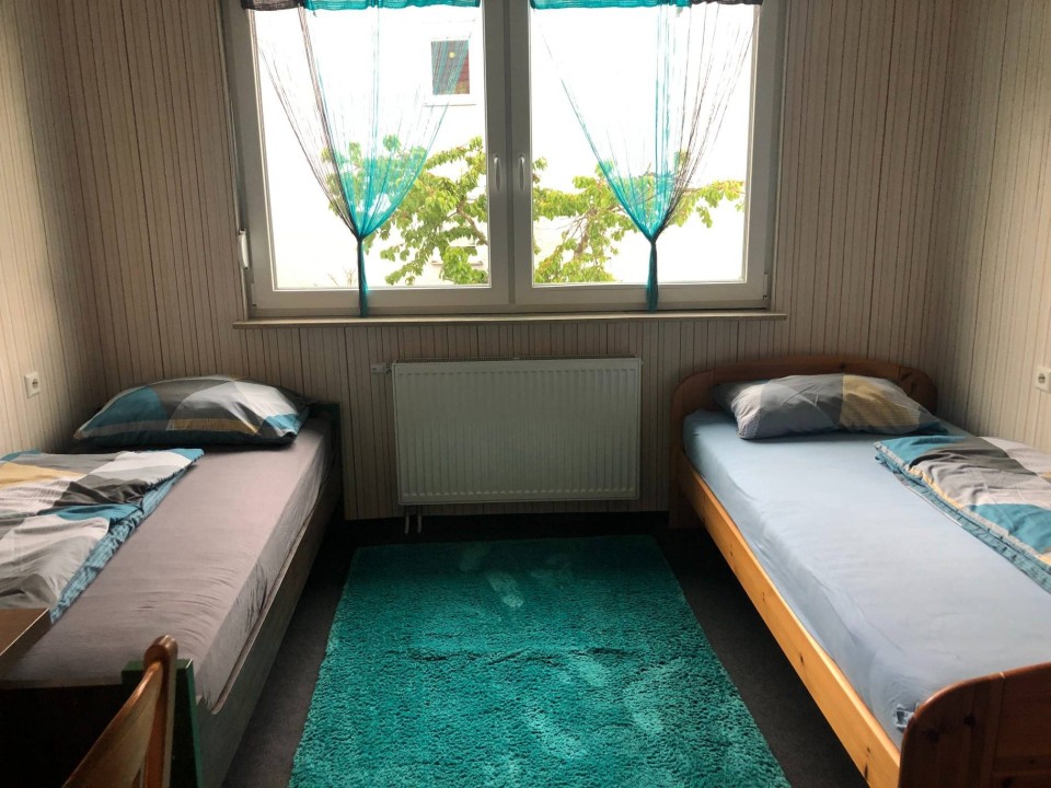Ein Schlafzimmer mit türkisem Teppich und Gardinen